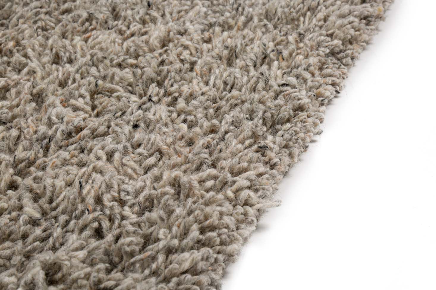 Een close-up van het Berbero Lungo Natural Grey 834 200x300 tapijt toont de getextureerde, ruige grijze vezels op een witte achtergrond. De dikke, zachte pool zorgt voor een pluche gevoel met een licht oneffen oppervlak.