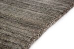 Close-up van het Portofino Grey 03 200x300 vloerkleed, met een gestructureerd, rechthoekig ontwerp met zacht geweven randen en subtiele donkere en lichte horizontale strepen, tegen een witte achtergrond.