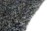 Close-up van de rand van het New Paulo Grey Blue 211 170x230 vloerkleed, met dikke shaggy vezels in donkergrijs en blauw tegen een witte achtergrond.