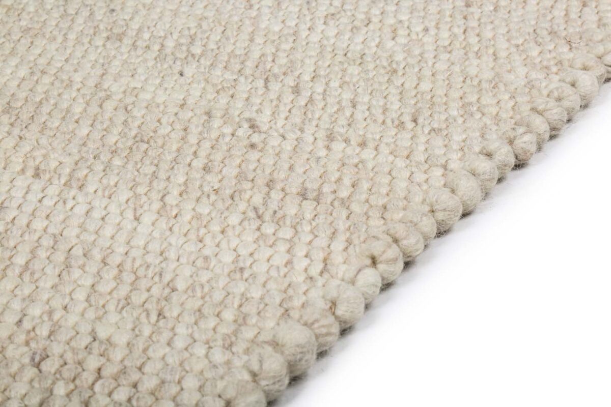 Een close-up van het Verona ST Cloud White 815 200x300 tapijt met een beige, geweven structuur met een dik, gelust patroon tegen een witte achtergrond.