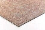 Close-up van een hoek van het Cirix dessin 2301 Spice 200x290 vloerkleed, met geweven details in beige, roze en lichtbruine tinten met een vervaagd geometrisch patroon op een wit oppervlak.