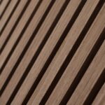 Close-up van de Akupanel Eiken Mokka 60 x 60 cm Lattenwand akoestische wandpanelen, met gelijkmatig verdeelde verticale latten in natuurlijk bruin met een gladde afwerking, waardoor een opvallend licht- en schaduwpatroon ontstaat.