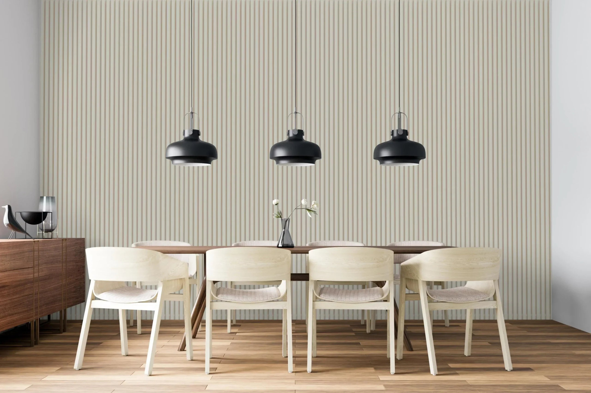 Een moderne eetkamer met een houten tafel, zes lichte stoelen, drie zwarte hangers, een dressoir en een minimaal decor met bloemen tegen een akoestische lamellenwand van Rosenwood Akupanel Beige op Beige 270x60 cm.