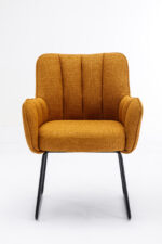 De Stoel Kevin Bjorn Fabric Mustard is een mosterdgele gestoffeerde fauteuil met verticale stiksels, schuine armleuningen en zwarte metalen poten, tegen een effen witte achtergrond.