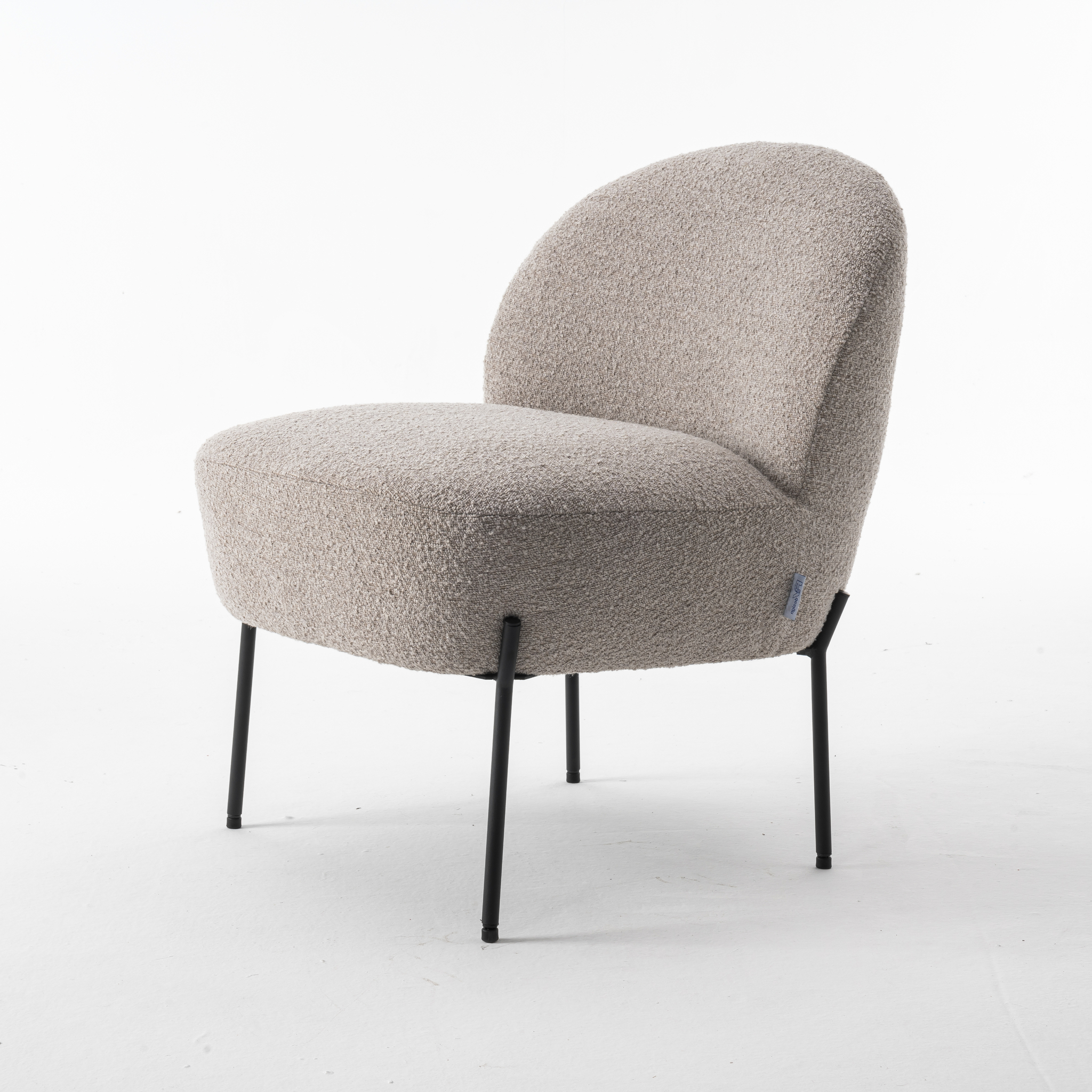 De Baudin fauteuil Stof Teddy Natural 01 is een moderne accentstoel met een afgeronde rugleuning, bekleed met lichtbeige structuurstof en slanke zwarte metalen poten in een hoek, afgebeeld op een effen witte achtergrond.