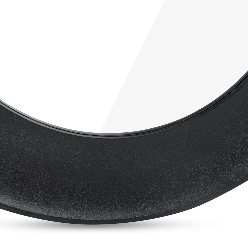 Close-up van de Spiegel Rond Zwart Groot, een ronde spiegel met een zwarte lijst met structuur, tegen een witte achtergrond. De gebogen lijst en een deel van het reflecterende glas zijn zichtbaar.