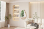Moderne woonkamer met crèmekleurige muren, een Spiegel 'Rana' 80x50 Oude eik (1c) spiegel, ingebouwde planken met decor, een witte bank met kussens en een deken, een plant in potten en grote ramen die natuurlijk licht binnenlaten.