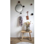 Een stijlvolle entree is voorzien van de Trapani spiegel met een zwart stalen frame en PU-band, muurhaken voor een sjaal en buidel, en een houten bankje met daarop een glazen vaas met gedroogde bloemen op een lichte houten vloer.