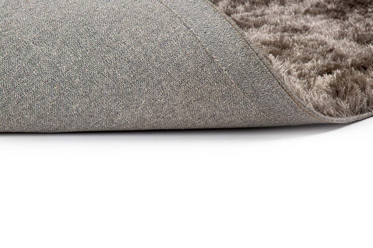 Close-up van het Arezzo ST Grey 803 170x230 tapijt met een omgedraaide hoek. De textuur van de antisliprug en het zachte, pluchen oppervlak tegen een witte achtergrond komen duidelijk naar voren.