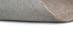 Close-up van Bellano ST Light Grey 814 ø200 hoektapijt omgedraaid, met het gestructureerde oppervlak en de rug tegen een witte achtergrond.