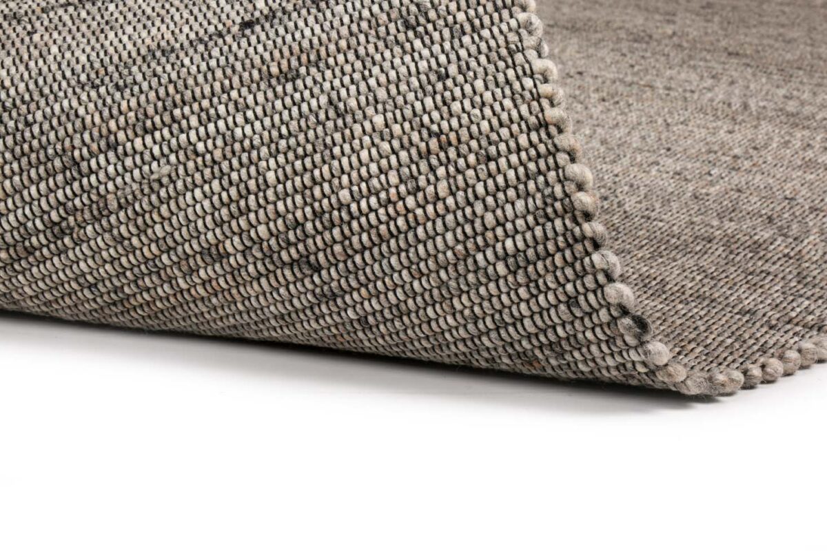 Een close-up van het Bressano Grey 834 200x300 vloerkleed, met een hoek omhoog om de geweven textuur en de lusvormige garens te laten zien, tegen een effen witte achtergrond.