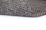 Close-up van de hoek van het Burano Anthracite 614-604 vloerkleed (170x230 cm), met een gestructureerd, geweven mandpatroon in grijs, getoond op een witte achtergrond.