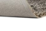 Een close-up van het New Paulo Grey mix 862 200x300 tapijt met een hoek opgetild, waardoor de gestructureerde rug en dikke, zachte pool aan de bovenkant zichtbaar worden.