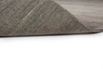 Een close-up van de hoek van het Portofino Beige 02 170x230 tapijt, omhoog gevouwen om de onderkant en het gestructureerde oppervlak te laten zien, tegen een witte achtergrond.