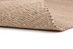 Een close-up van het Verona ST Beige 142 200x300 tapijt toont de dikke, gestructureerde lussen en de opgetilde rand om de onderkant te onthullen, allemaal tegen een witte achtergrond.
