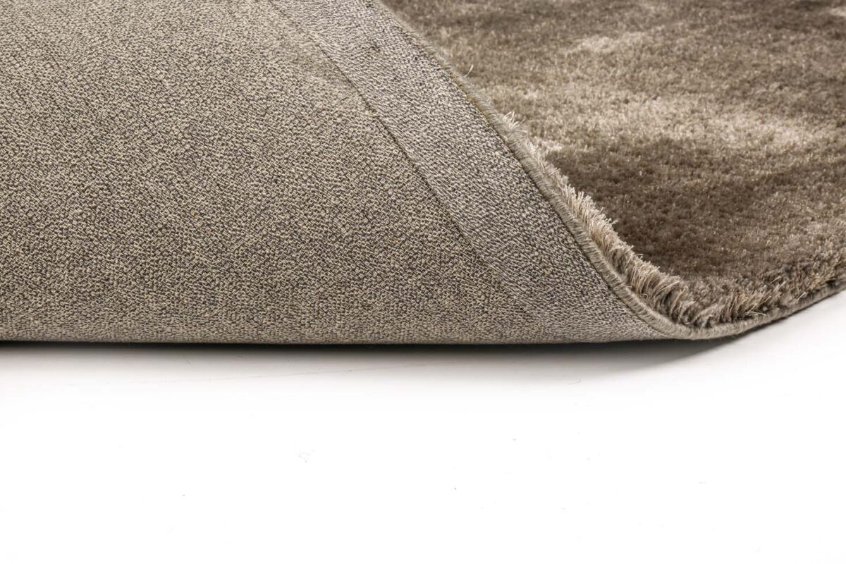 Close-up van de hoek van het Viterbo ST Grey 803 200x300 vloerkleed in grijs en beige, met de rand omhoog om de achterkant te laten zien, tegen een witte achtergrond.