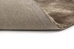 Close-up van de hoek van het Viterbo ST Grey 803 200x300 vloerkleed in grijs en beige, met de rand omhoog om de achterkant te laten zien, tegen een witte achtergrond.