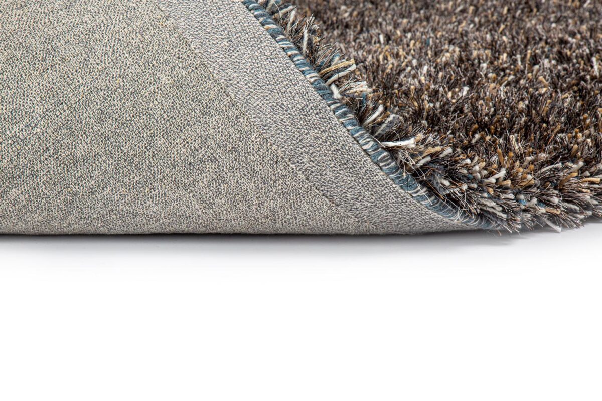 Een close-up van de hoek van het New Paulo Dark Blue/Bronze 270 170x230 tapijt onthult de geweven onderkant en de dikke pool met textuur tegen een witte achtergrond.