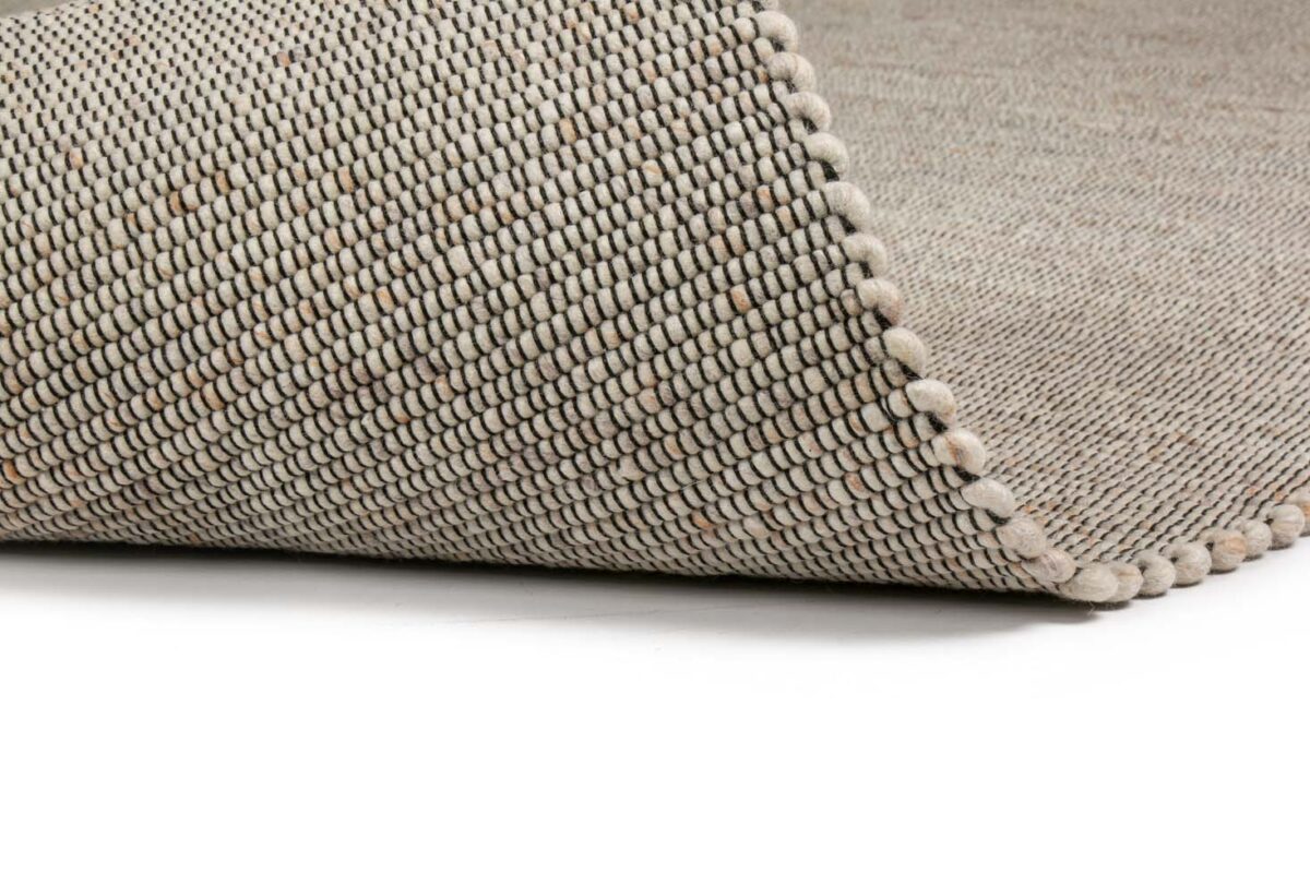 Een close-up van het Bressano Light Beige 141 200x300 vloerkleed benadrukt het getextureerde weefsel en de dikke, afgeronde rand, een toonbeeld van vakmanschap.