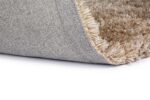 Close-up van de hoek van het New Paulo Light Beige mix 126 200x300 tapijt, opgetild om het beige-bruine shaggy oppervlak en de grijs geweven rug tegen een witte achtergrond te onthullen.