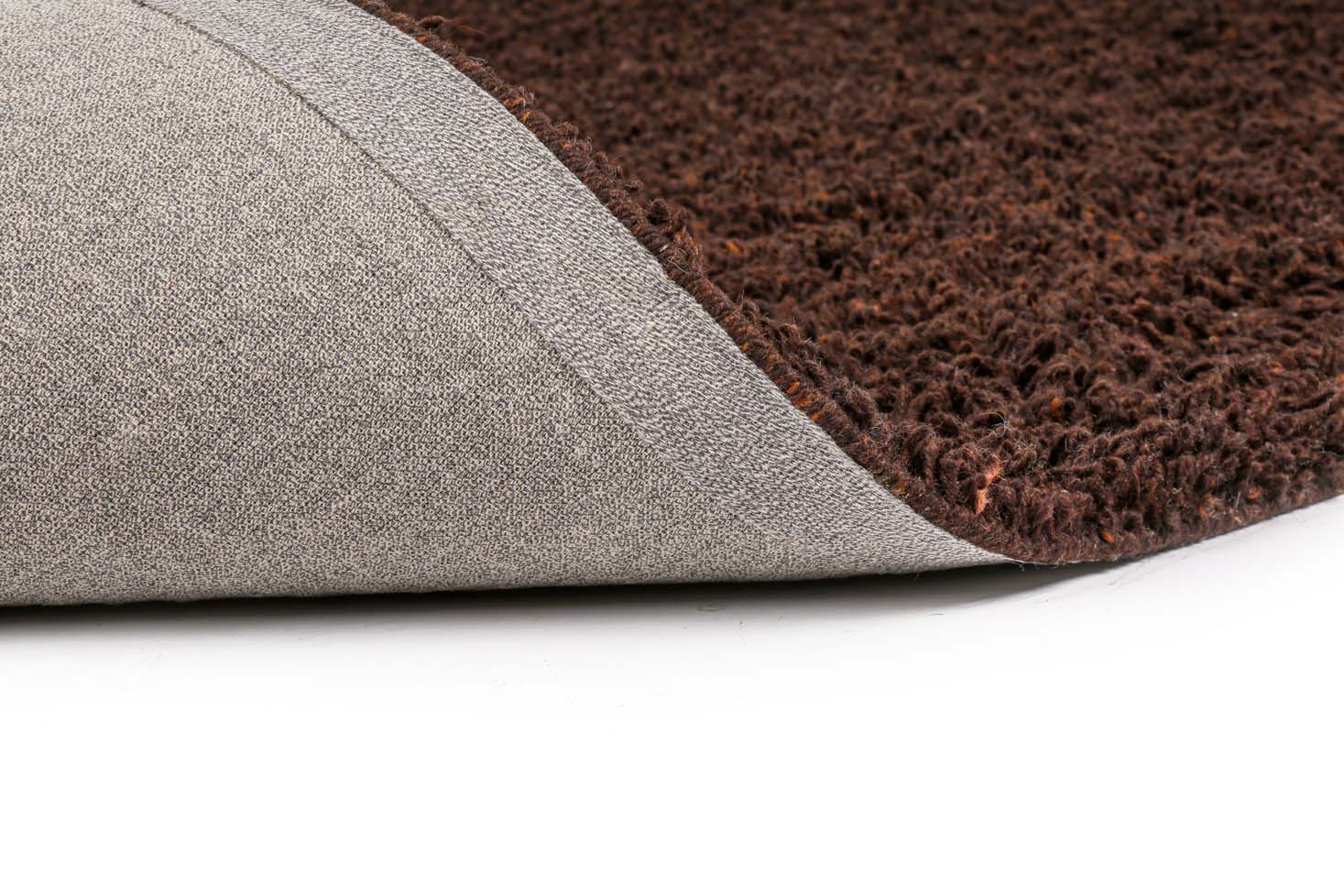 Een close-up van het Berbero Lungo Natural Beige 522 vloerkleed (170x230) met een bruin gestructureerd oppervlak en een omgedraaide hoek om de grijze antisliprug te onthullen, alles op een witte achtergrond.