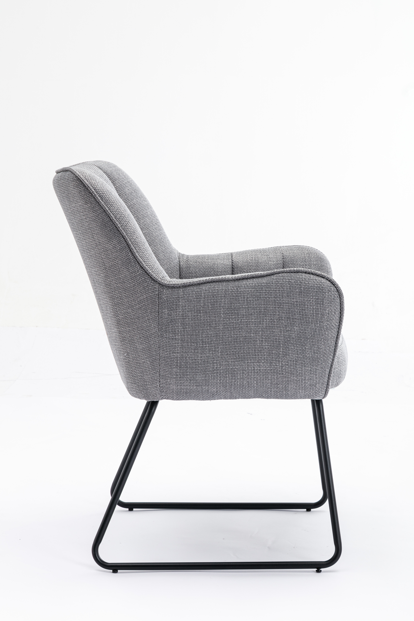 Zijaanzicht van de Stoel Kevin Bjorn Fabric Light Grey met zwarte metalen sledepoten, een licht achteroverleunende rugleuning en een comfortabele zitting met kussens, tegen een effen witte achtergrond.