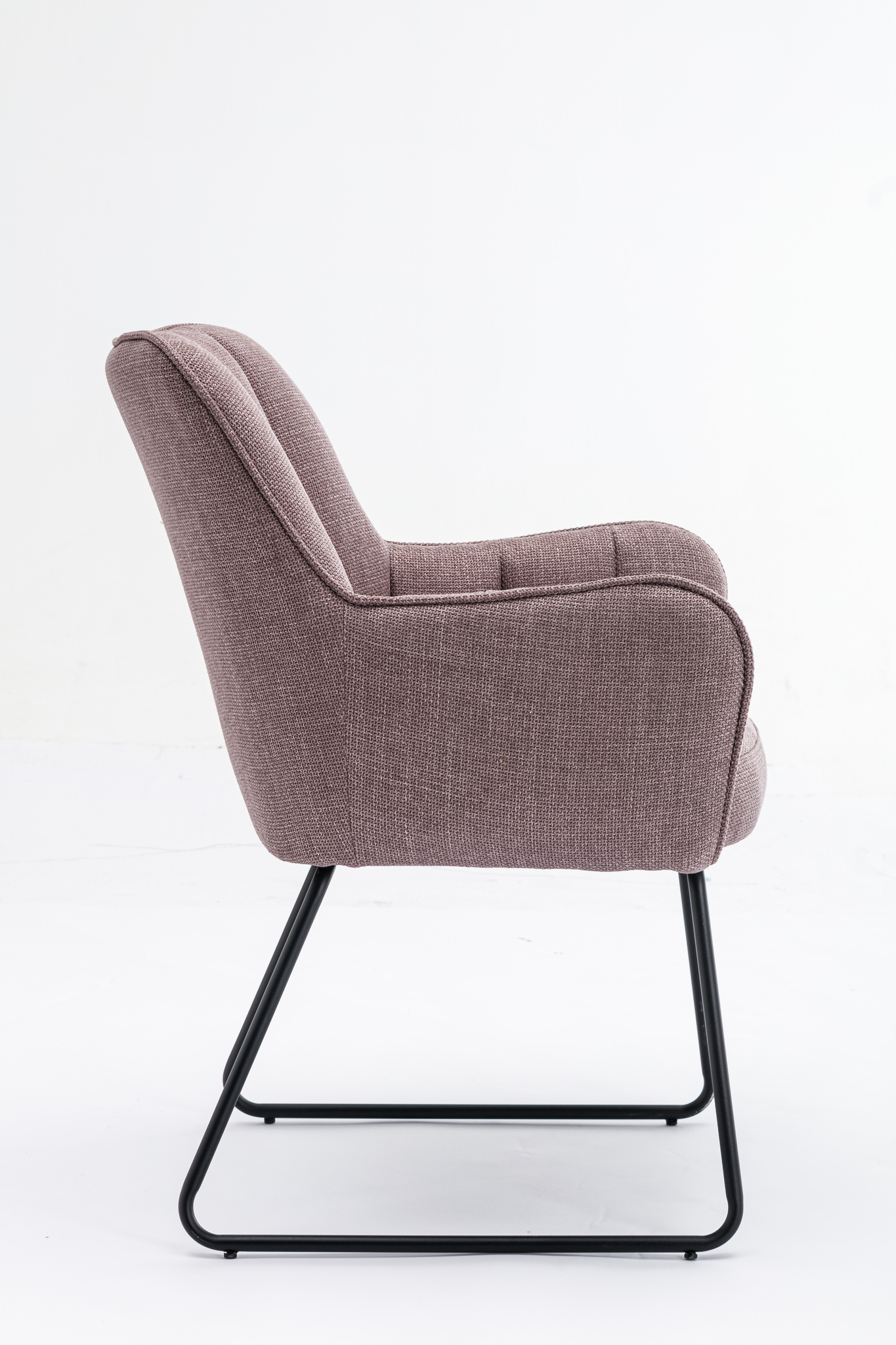 De Stoel Kevin Bjorn Fabric Lavender is een moderne stoel met mauve stoffering, een licht achteroverleunende rugleuning en zwarte metalen sledepoten, afgebeeld in zijaanzicht tegen een effen witte achtergrond.