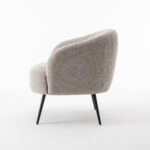 De Laura fauteuil Stof Teddy Natural 01 is een modern gestoffeerde fauteuil met lichtbeige structuurstof, een afgeronde rugleuning en zitting en vier slanke zwarte metalen poten, van opzij gezien tegen een witte achtergrond.