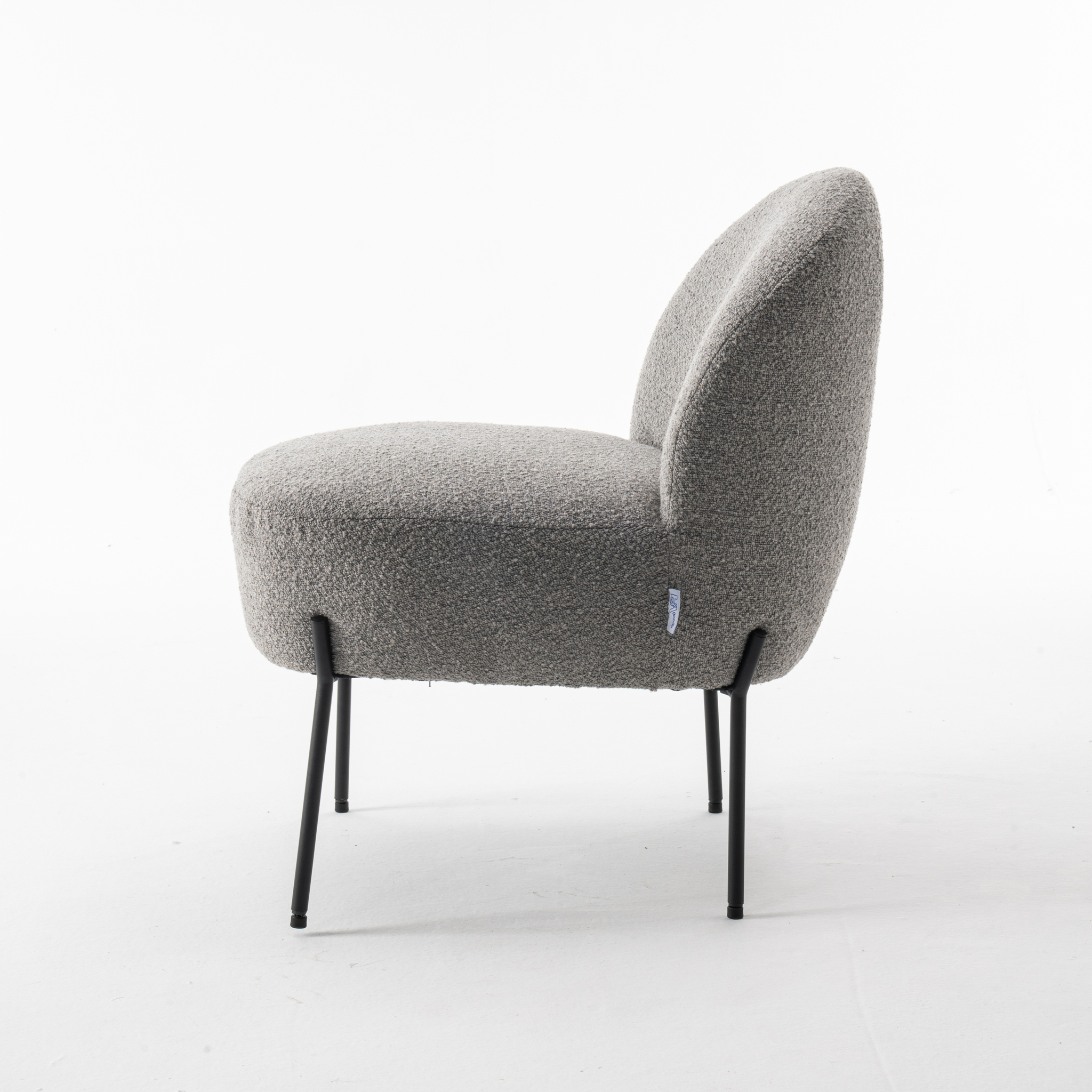 De Baudin fauteuil Stof Teddy Steel 149 is een moderne, armloze stoel met een afgeronde rugleuning en een pluche bekleding met grijze textuur, ondersteund door vier slanke zwarte metalen poten, afgebeeld tegen een effen witte achtergrond.