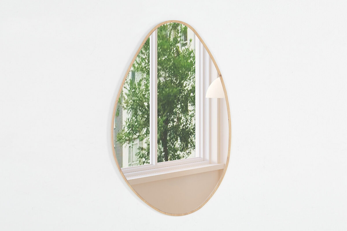 De Spiegel 'Rana' 80x50 Oude eik (1c) hangt aan een witte muur en weerspiegelt een raam met groene loofbomen en een deel van een witte lamp in de kamer.