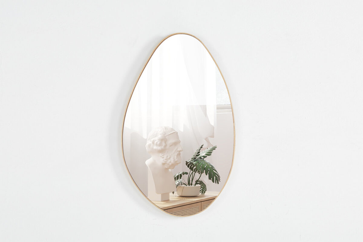 De Spiegel 'Romi' 80x50 Oude eik (1c) wandspiegel weerspiegelt een buste sculptuur, een groene potplant en een raam met transparante gordijnen in een minimalistische kamer.