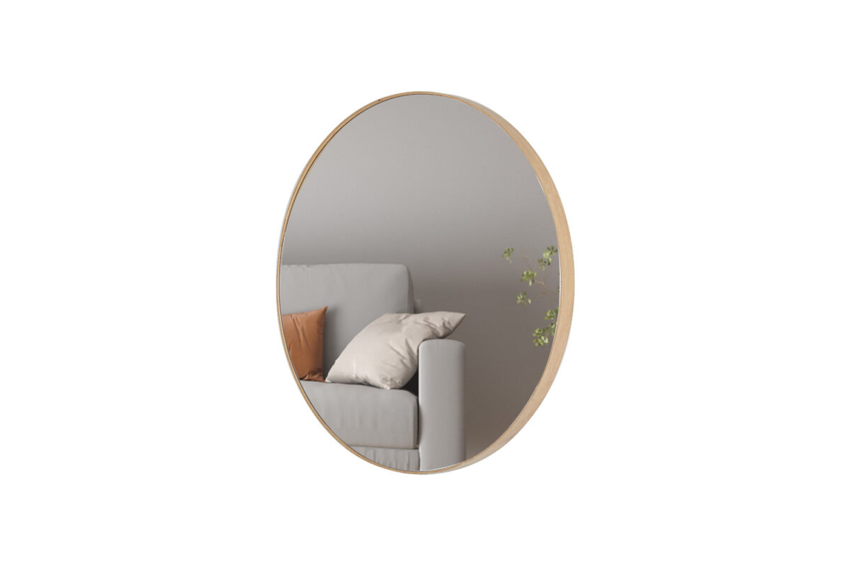 De Spiegel 'Ria' 80x80 Oude eik (1c) ronde spiegel met een houten lijst weerspiegelt een grijze bank met beige en bruine kussens, plus een kleine groene plant in een minimalistische setting.