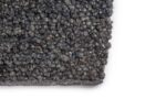 Close-up van de hoek van het vloerkleed Modena Grey 916 200x300, met grof gebreide textuur en dik garen op een witte achtergrond.