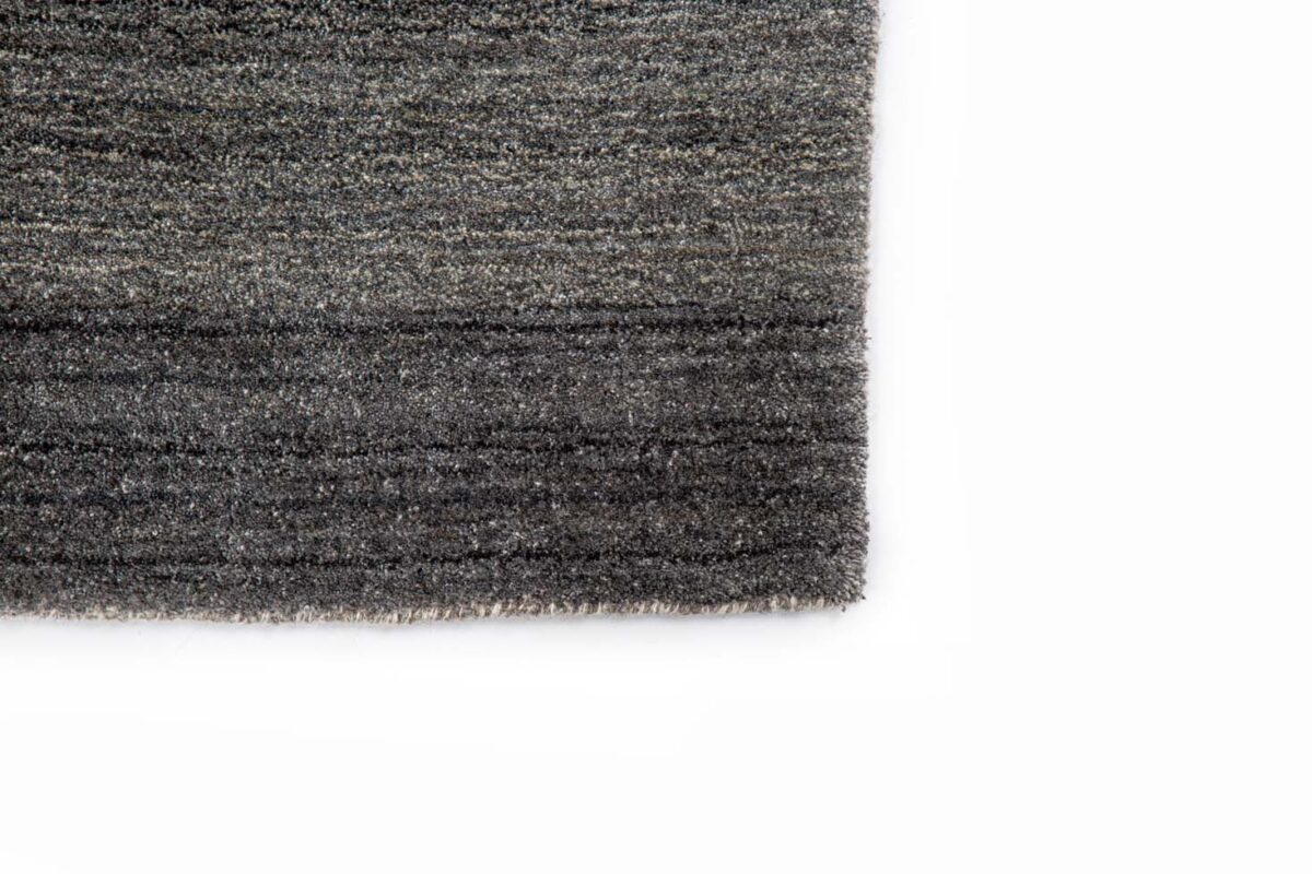 Close-up van de hoek van het Portofino Grey 03 200x300 vloerkleed, met een grijs gestructureerd oppervlak met subtiele horizontale lijnen, tegen een witte achtergrond.
