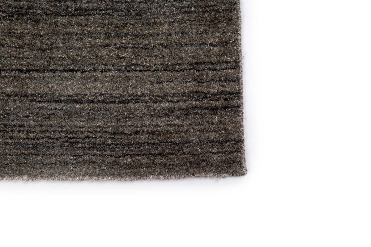 Close-up van Portofino Beige 02 170x230 tapijthoek met rechthoekige vorm, gestructureerd oppervlak en donkergrijze en zwarte horizontale lijnen op een lichtgrijze achtergrond, getoond tegen een wit oppervlak.