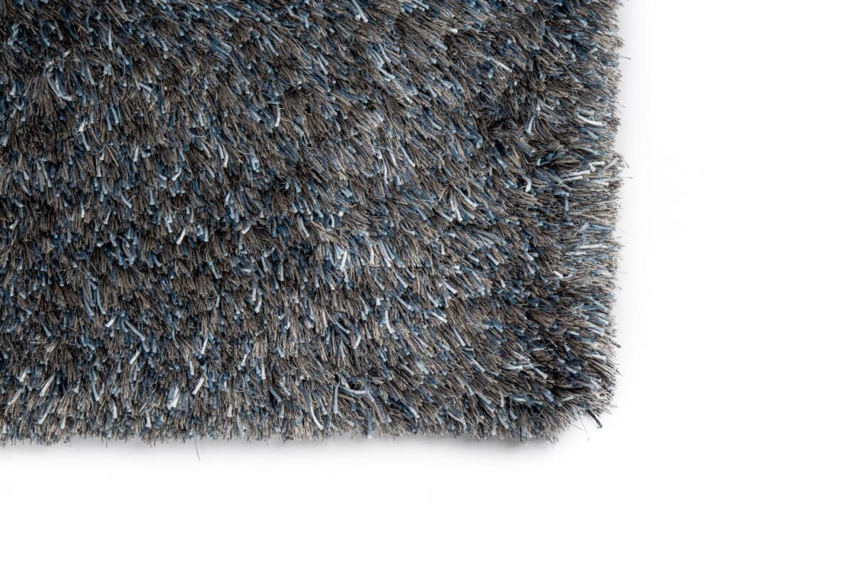 Close-up van de hoek van het New Paulo Grey Blue 211 170x230 vloerkleed op een witte achtergrond, met de dikke, pluche vezels en het dichte, gestructureerde oppervlak.