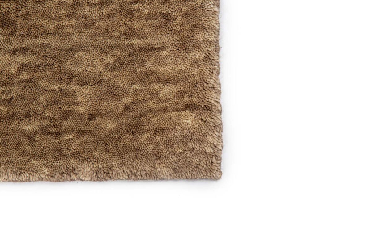 Close-up van het San Stefano Camel 09 200x300 tapijt, met dicht opeengepakte, zachte vezels en een pluche, getextureerd oppervlak in een gevlekt camelbruin patroon. De afbeelding benadrukt de gedetailleerde rand en knusse uitstraling.