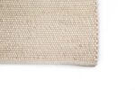 Close-up van de hoek van het Verona ST Cloud White 815 200x300 tapijt, met het eenvoudige geweven beige patroon tegen een witte achtergrond.
