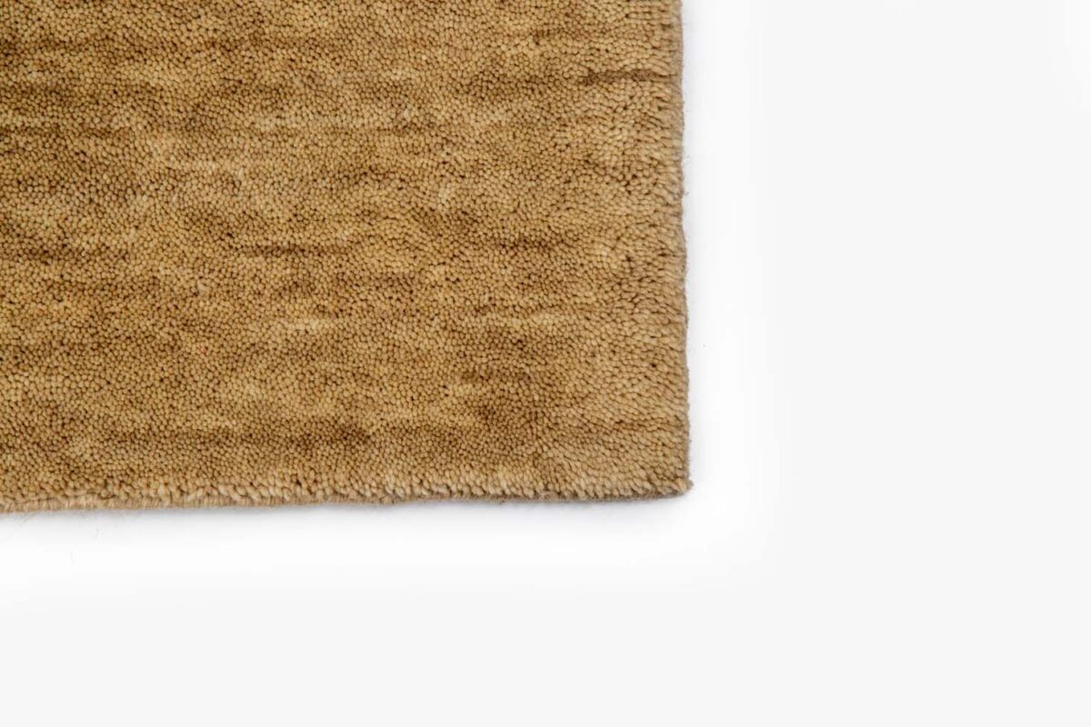 Close-up van de hoek van het vloerkleed San Stefano Light Beige 07 (200x300), met het gestructureerde oppervlak en de licht onregelmatige rand op een witte achtergrond.