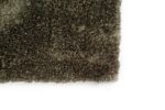Close-up van de hoek van het Viterbo ST Hunter 421 200x300 donkerbruine shaggy tapijt met textuur tegen een witte achtergrond.
