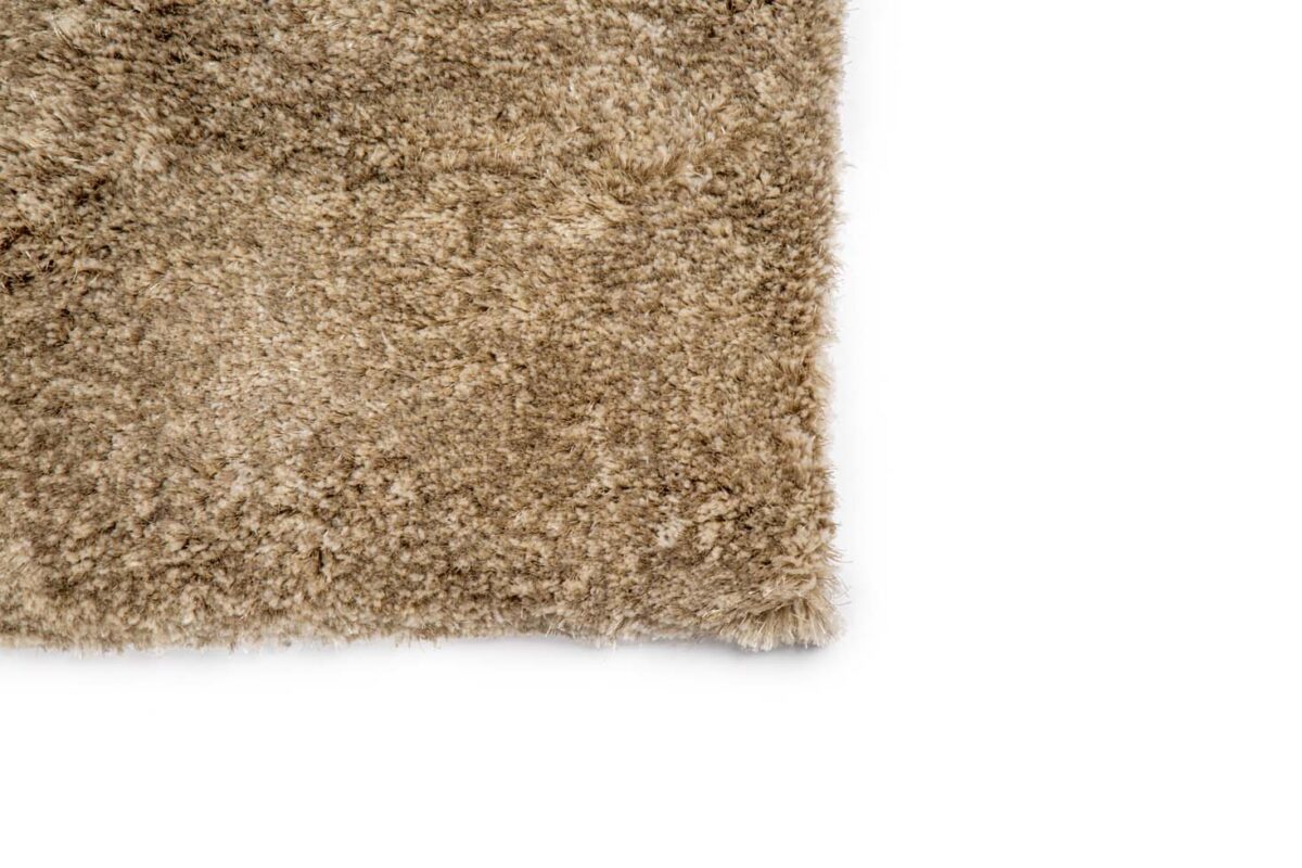 Een close-up van de hoek van de Viterbo ST Silver 119 200x300 beige, donzig tapijt op een witte achtergrond.