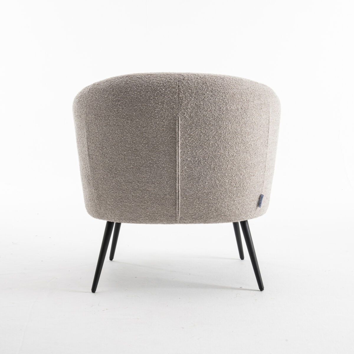De Laura fauteuil Stof Teddy Natural 01 is een moderne ronde beige fauteuil met gestructureerde bekleding en slanke zwarte metalen poten, van achteren gezien tegen een effen witte achtergrond.