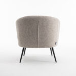 De Laura fauteuil Stof Teddy Natural 01 is een moderne ronde beige fauteuil met gestructureerde bekleding en slanke zwarte metalen poten, van achteren gezien tegen een effen witte achtergrond.