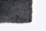 Een close-up van het Merano Charcoal 013 200x300 shagtapijt toont de donkergrijze, donzige textuur tegen een effen witte achtergrond.