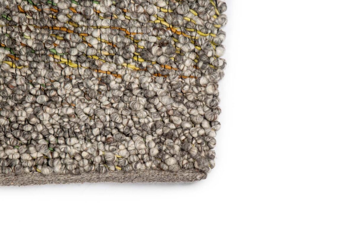 Close-up van de hoek van het Modena Beige 840 170x230 vloerkleed, met gestructureerd, geweven grijs en beige garen met subtiele gele en groene accenten, tegen een effen witte achtergrond.