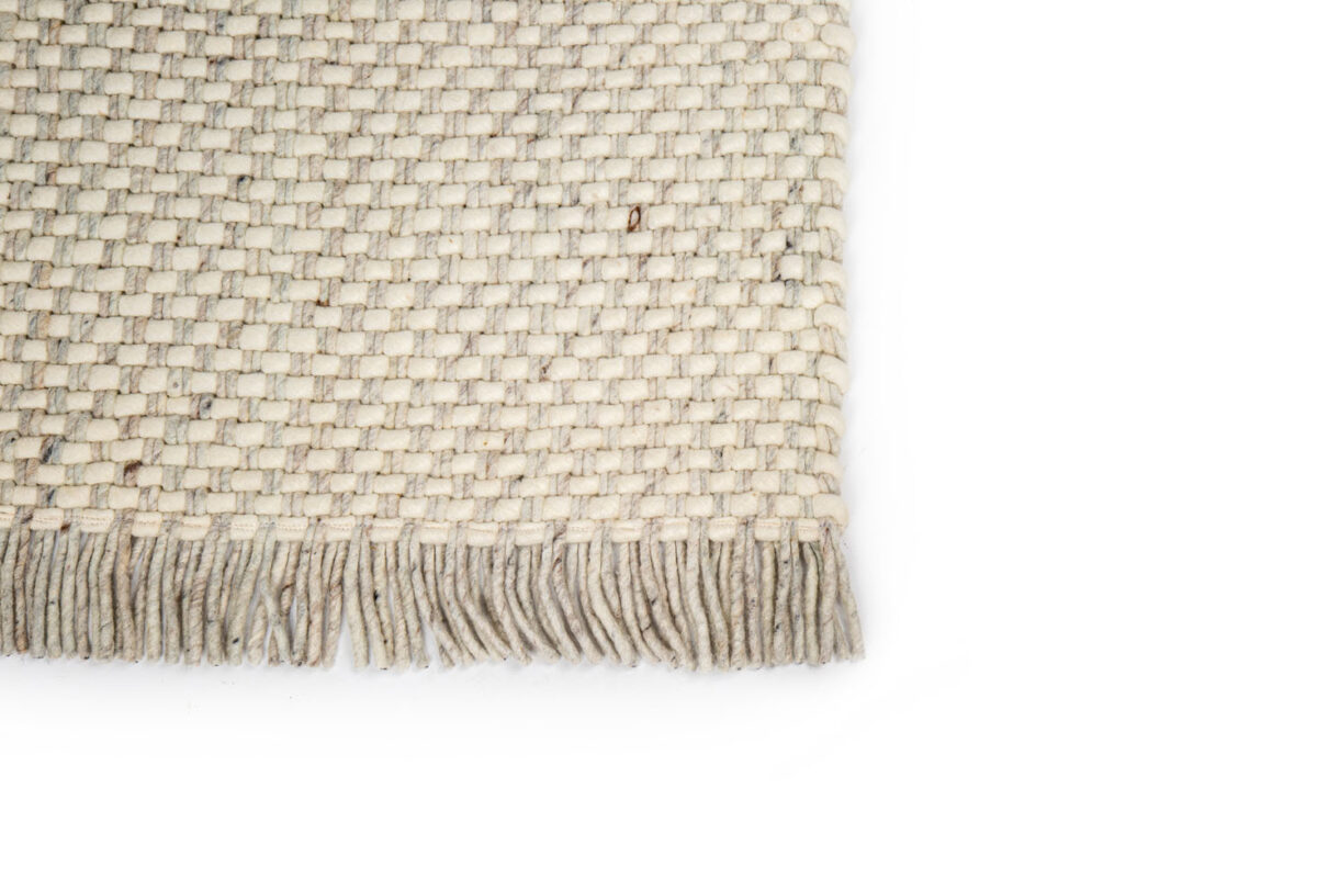 Een close-up van het Burano White Grey 001-367 170x230 vloerkleed met een beige geweven structuurpatroon met franjes tegen een witte achtergrond.