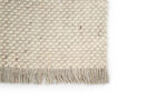 Een close-up van het Burano White Grey 001-367 170x230 vloerkleed met een beige geweven structuurpatroon met franjes tegen een witte achtergrond.