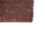 Close-up van de hoek van het vloerkleed Modena Brown Anthracite 522 200x300. Het geweven oppervlak met bruine tinten en subtiele rode en oranje draden tegen een witte achtergrond.