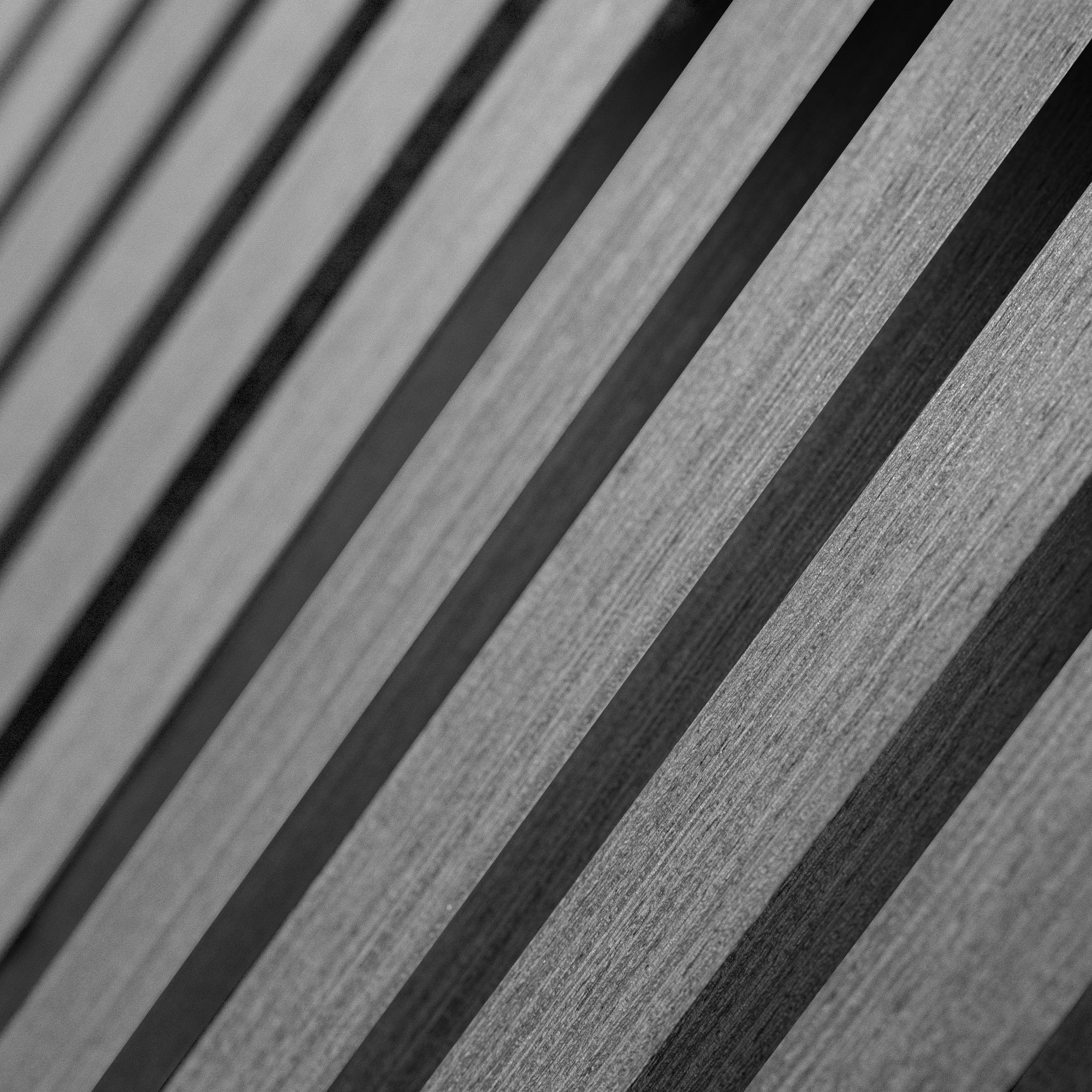 Close-up van Akupanel Eiken Grijs 270 x 60 cm latwand akoestische wandpanelen, met parallelle diagonale houten latten met zichtbare textuur en een zich herhalend geometrisch patroon in grijstinten.