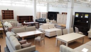 Verschillende soorten meubels met prijskaartjes in een showroom, waaronder banken, tafels en kasten met gemiddelde prijs meubels